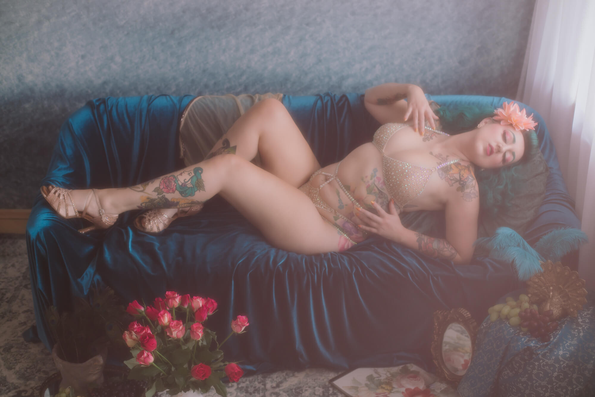 Fotografia sensualna kobiety z tatuażami, leżącej w zmysłowej pozie na kanapie