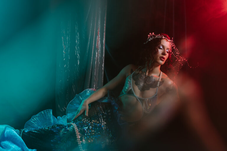 Kobieta w mrocznym turkusowo czerwonym świetle ma na sobie syreni ogon.