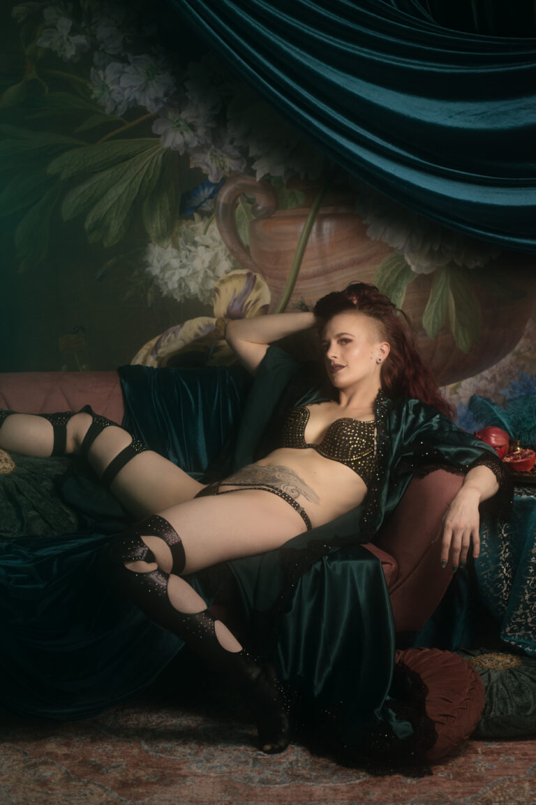 Kobieta w satynowym turkusowym szlafroku siedzi na sofie.